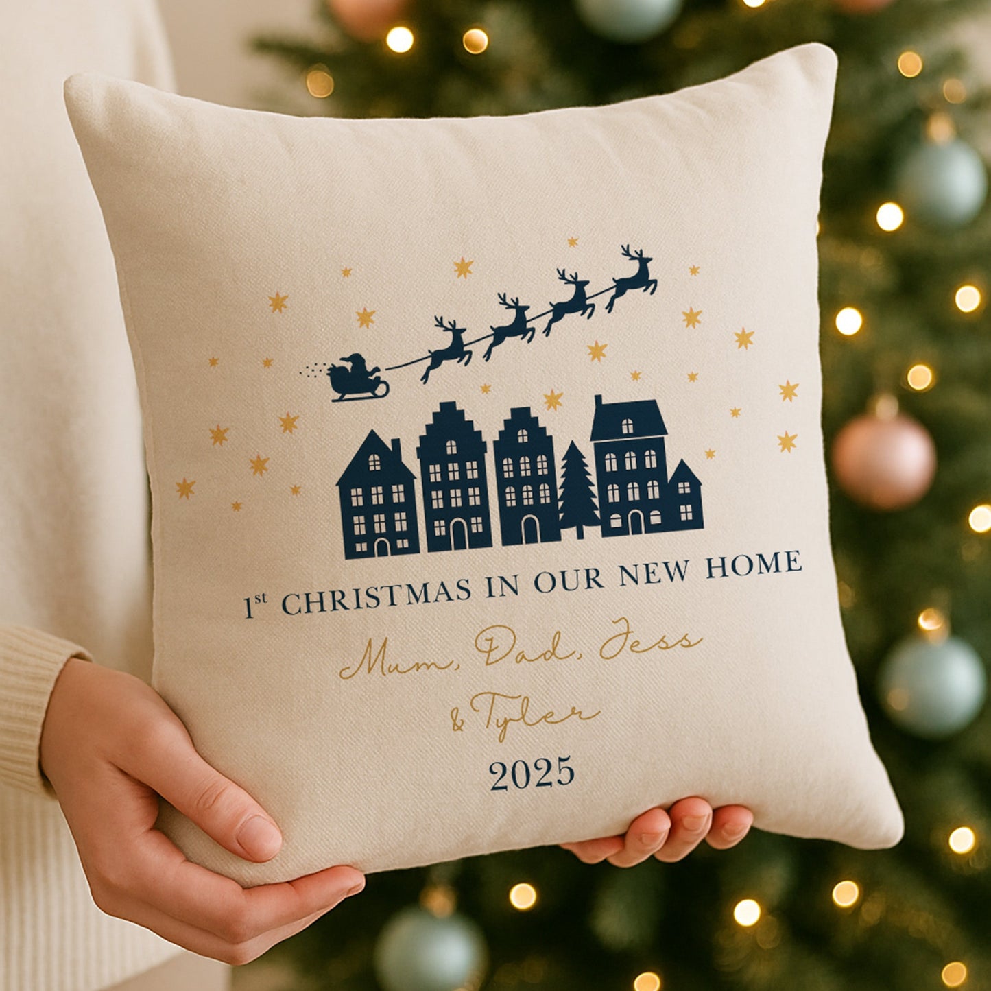 Decorative pillow with Christmas text held in front of a decorated tree