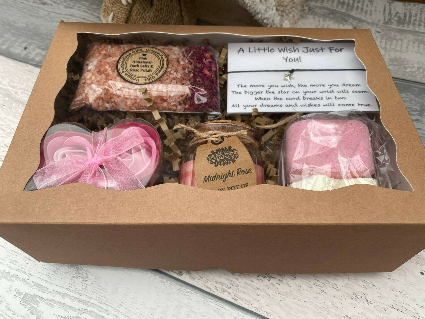 Gift set with bath bombs and a candle in a cardboard box on a wooden surface.