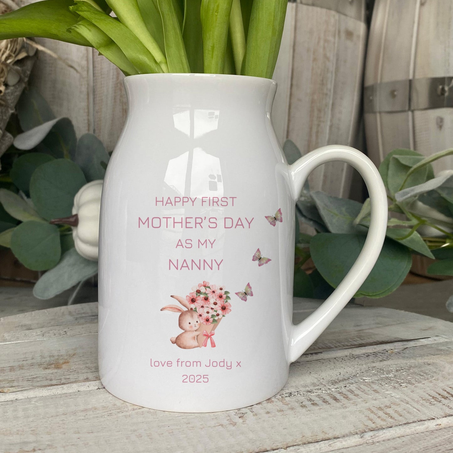 Personalised ceramic jug with 'Happy First Mother's Day as my Nanny' message, featuring a bunny holding flowers and butterflies, perfect gift from grandchild