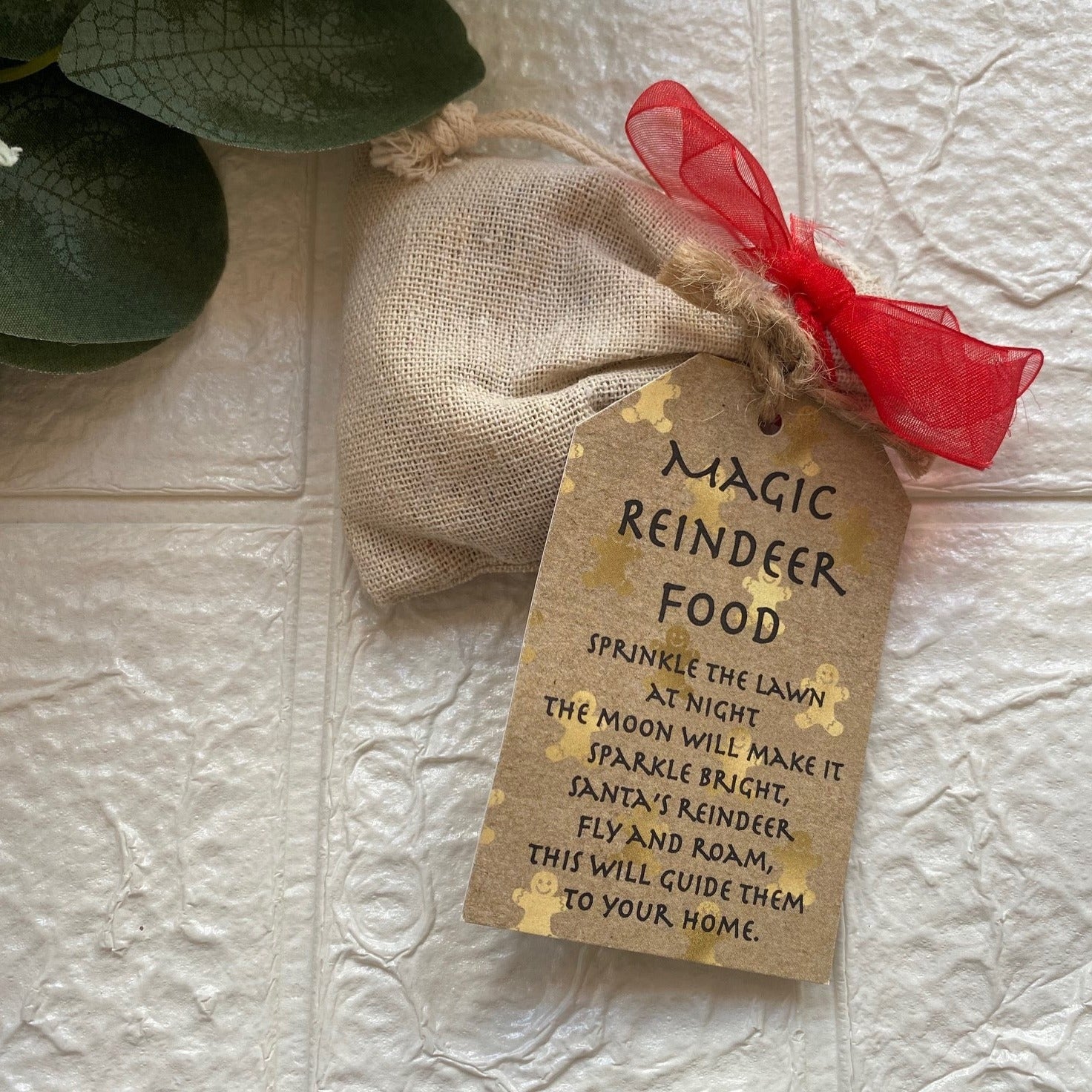 Burlap bag with red ribbon and 'Magic Reindeer Food' tag on textured surface