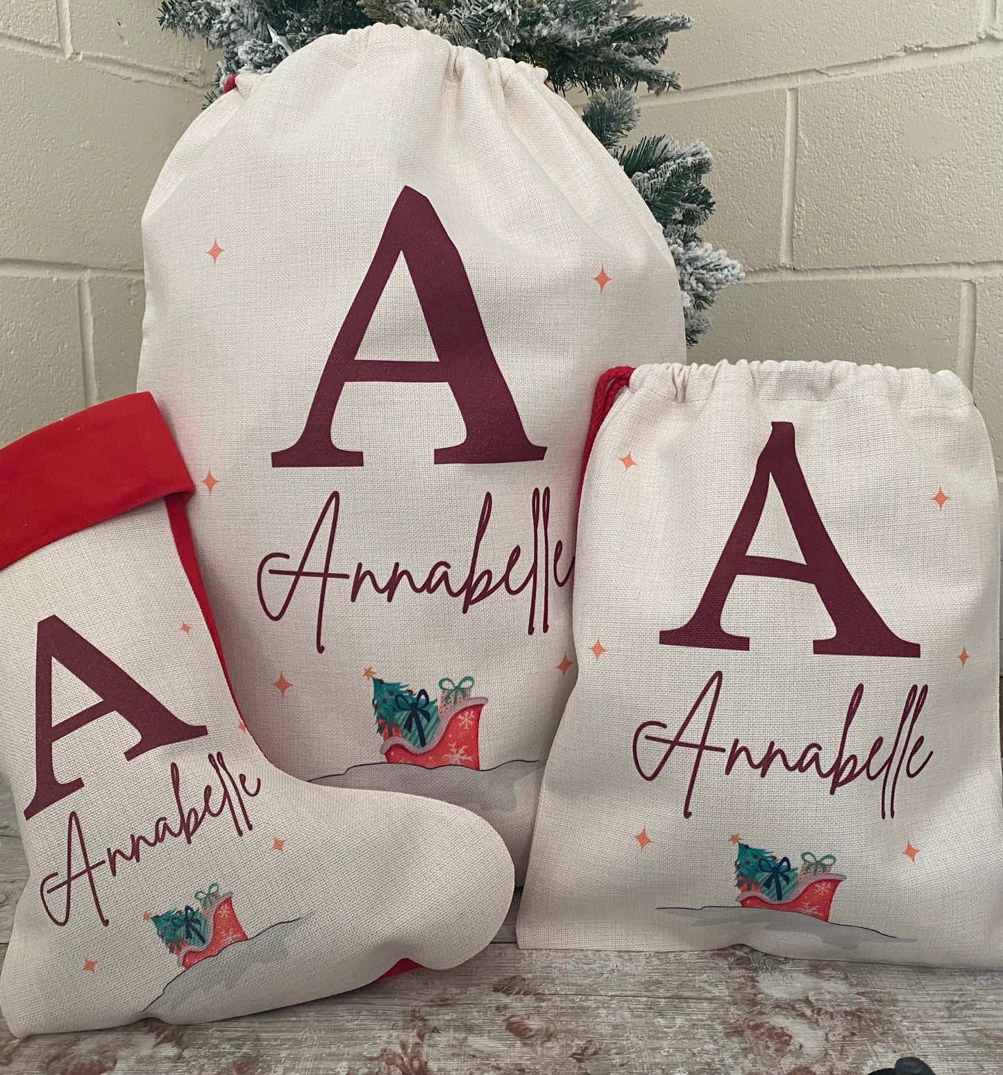 Personalised Christmas gift sack, stocking, and drawstring bag set for child named Annabelle, featuring large red initial 'A', festive red boot illustration with presents, and soft neutral fabric – ideal custom Christmas gift packaging for kids.