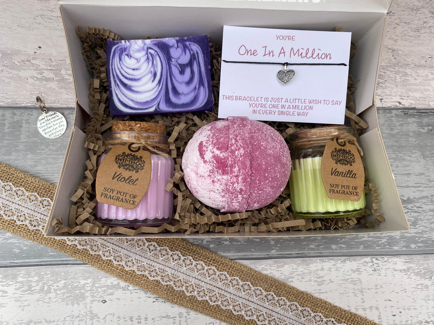 Gift set with bath bombs, candles, and a bracelet in a box on a wooden surface.