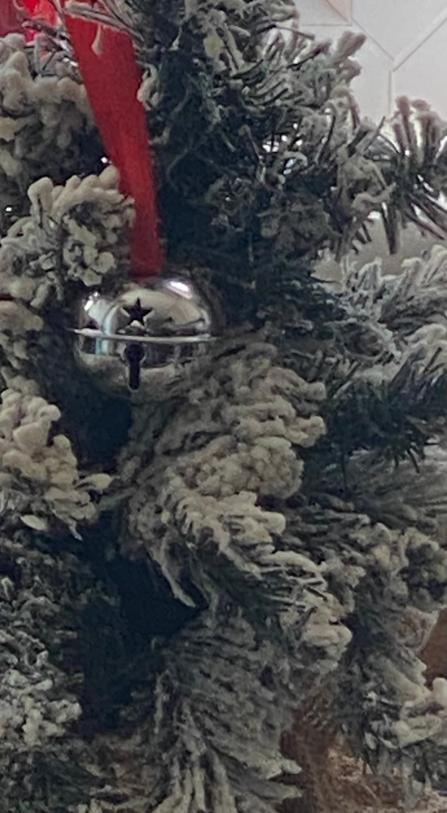 Silver bell ornament on a Christmas tree