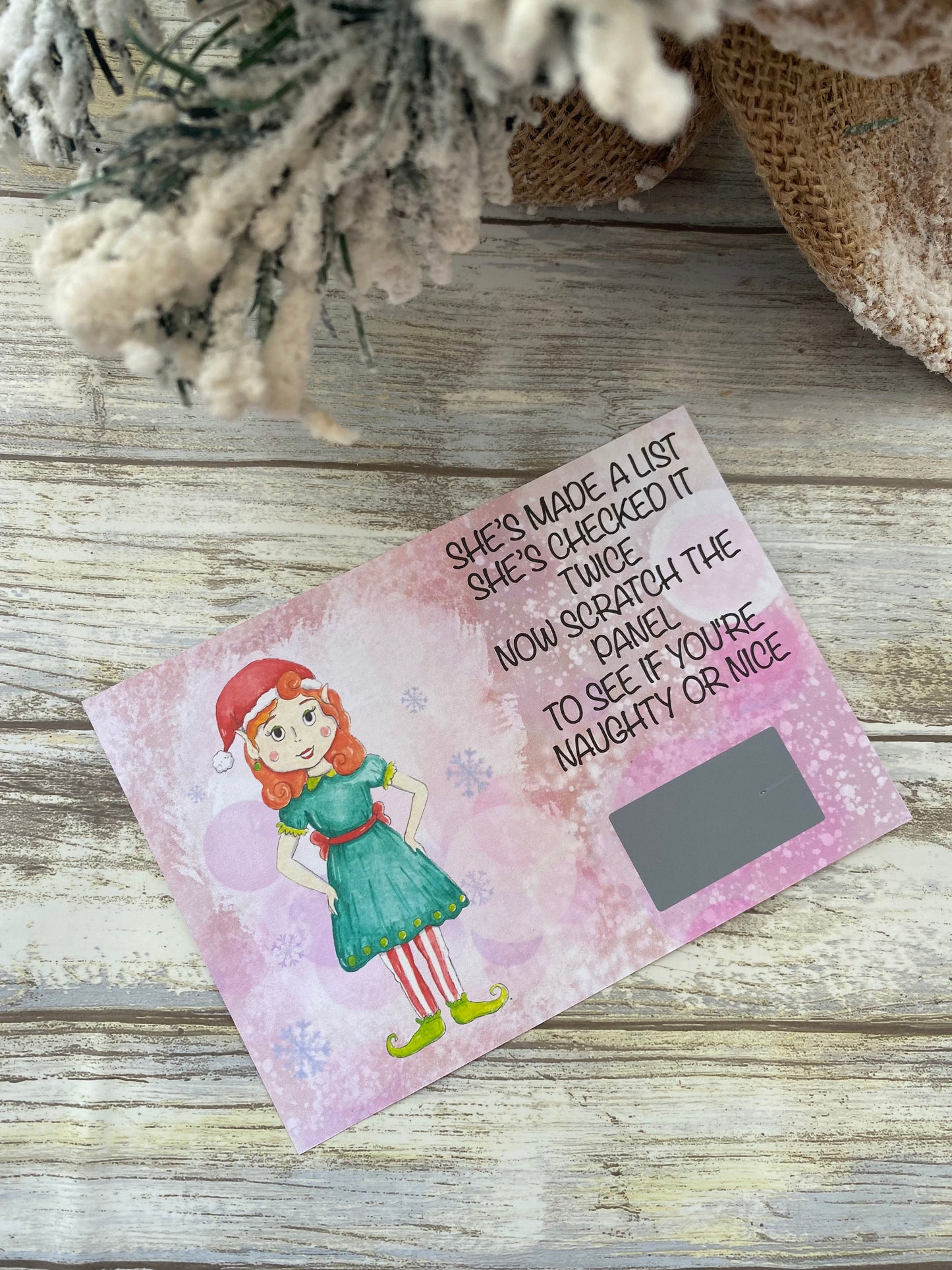 Scratch card with a Christmas Elf on a wooden surface