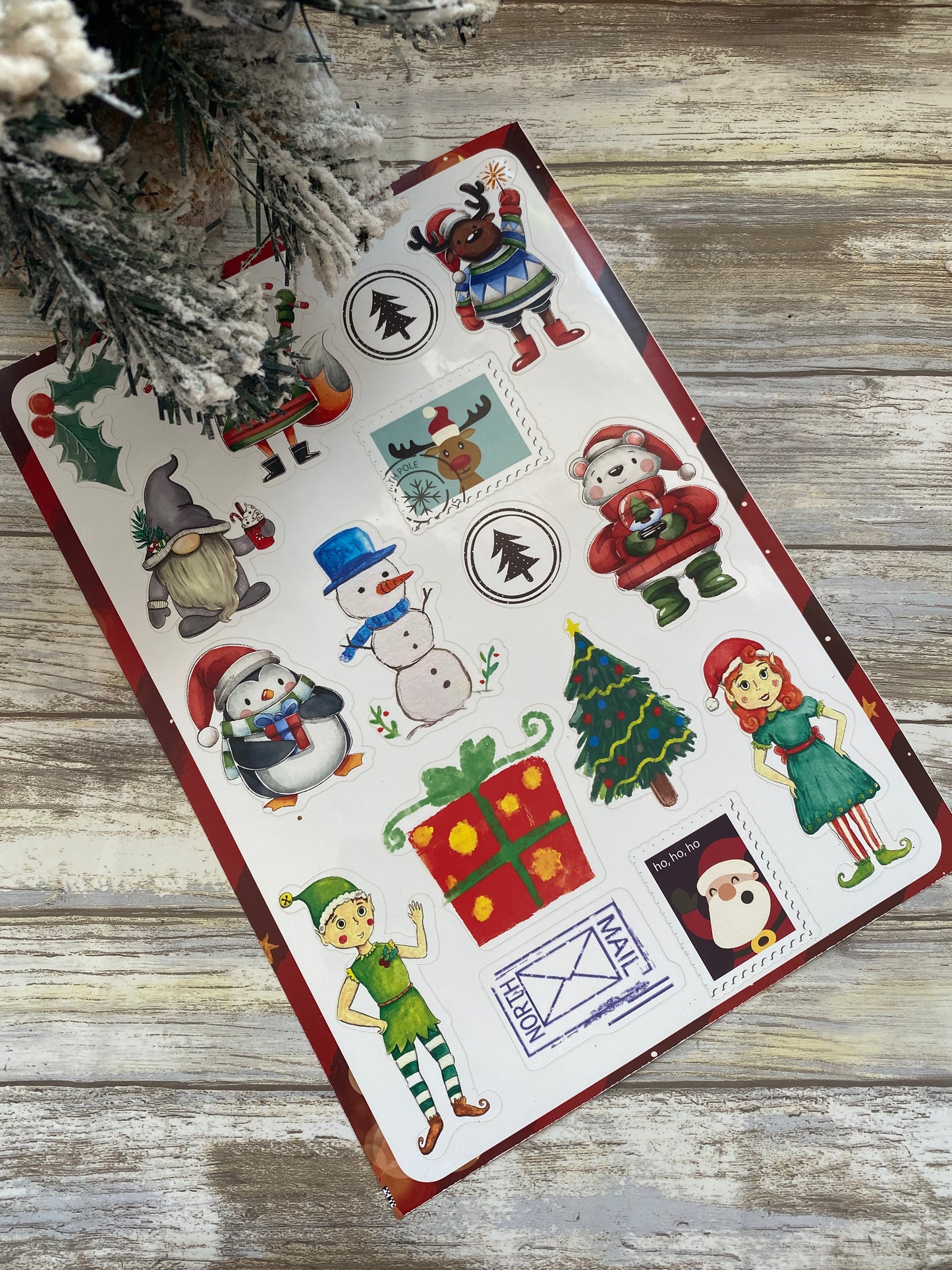 Sheet of Christmas-themed stickers on a wooden surface with decorative elements.