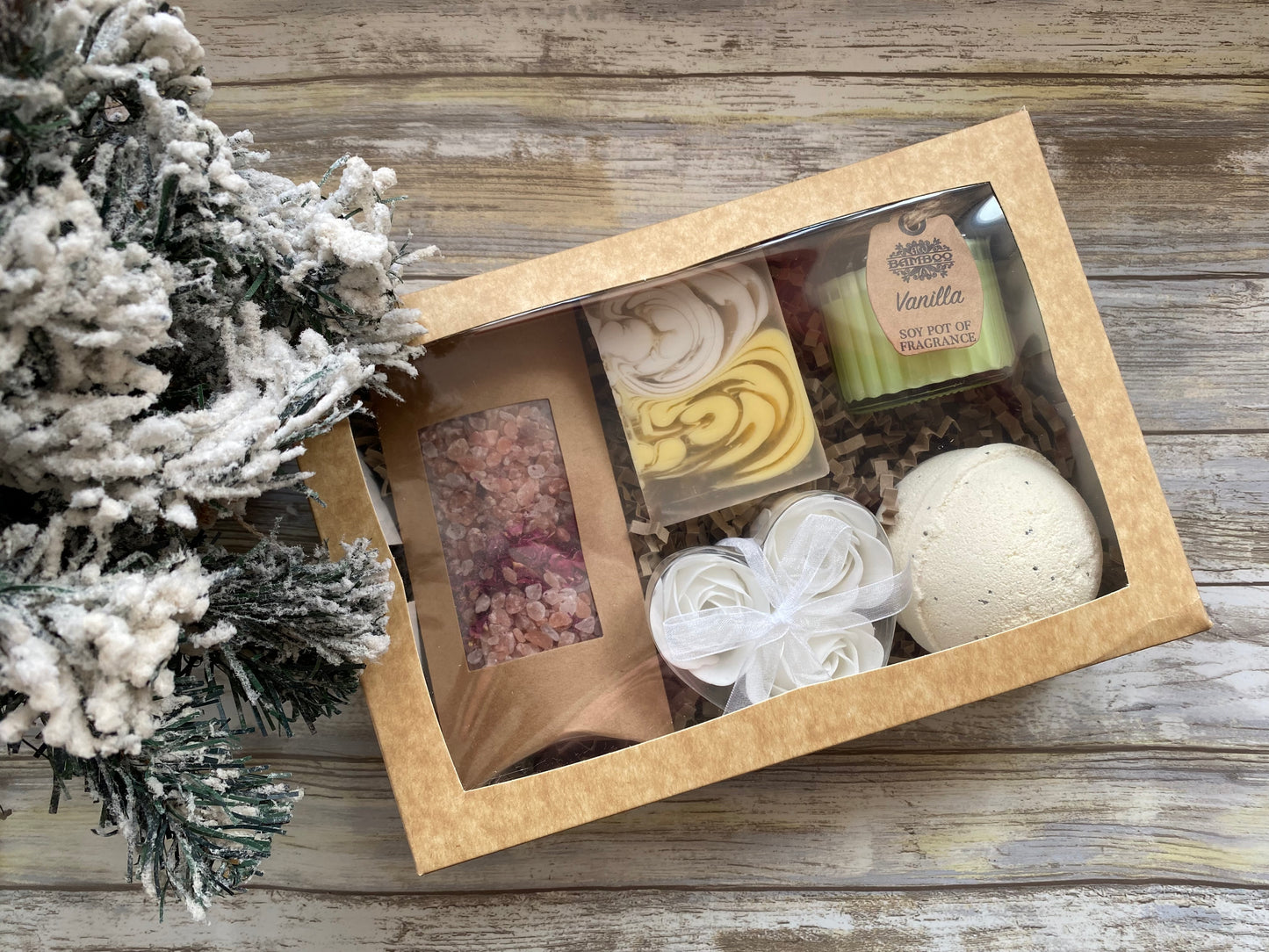 Bath product set with candles, soap, and bath bombs in a box on a wooden surface.