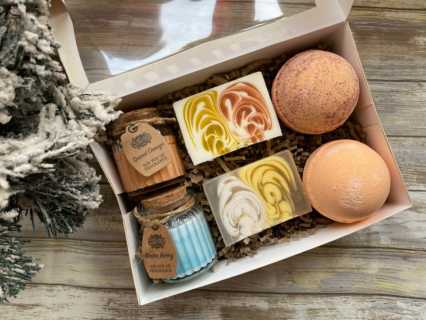 Bath bomb and candle set in a box on a wooden surface with decorative elements.