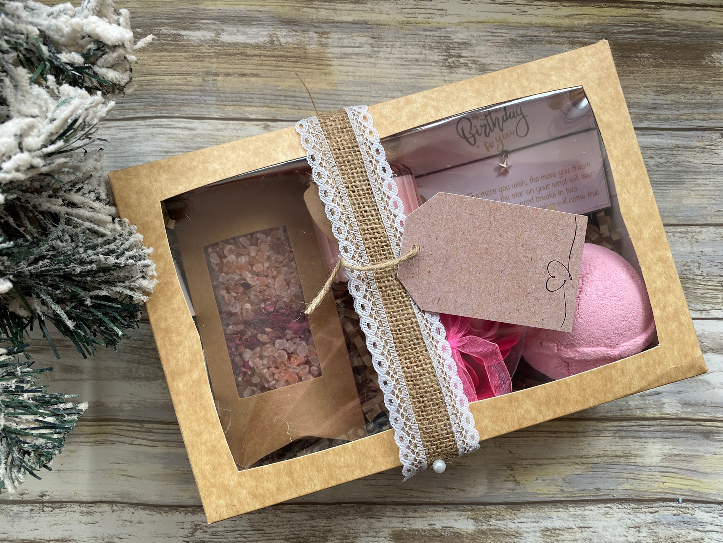 Gift set with bath bomb and soap in a decorative box on a wooden surface.