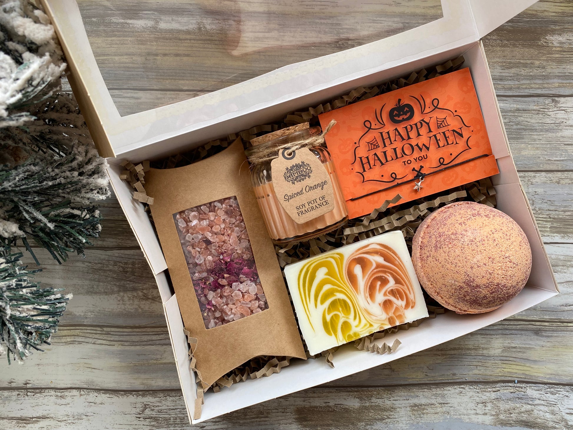 Box of Halloween-themed products including a bath bomb and soap on a wooden surface.