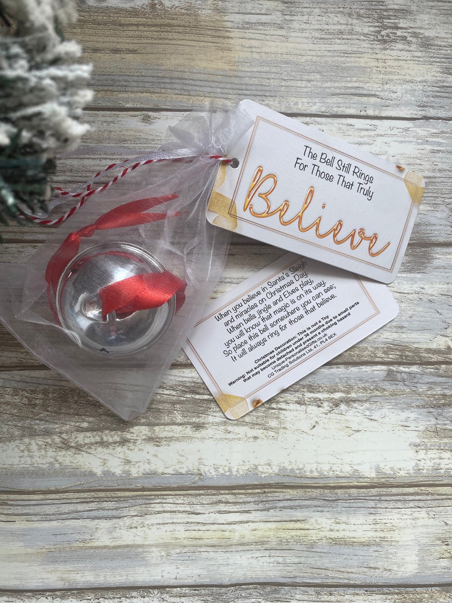 Decorative bell with ribbons and cards on a wooden surface