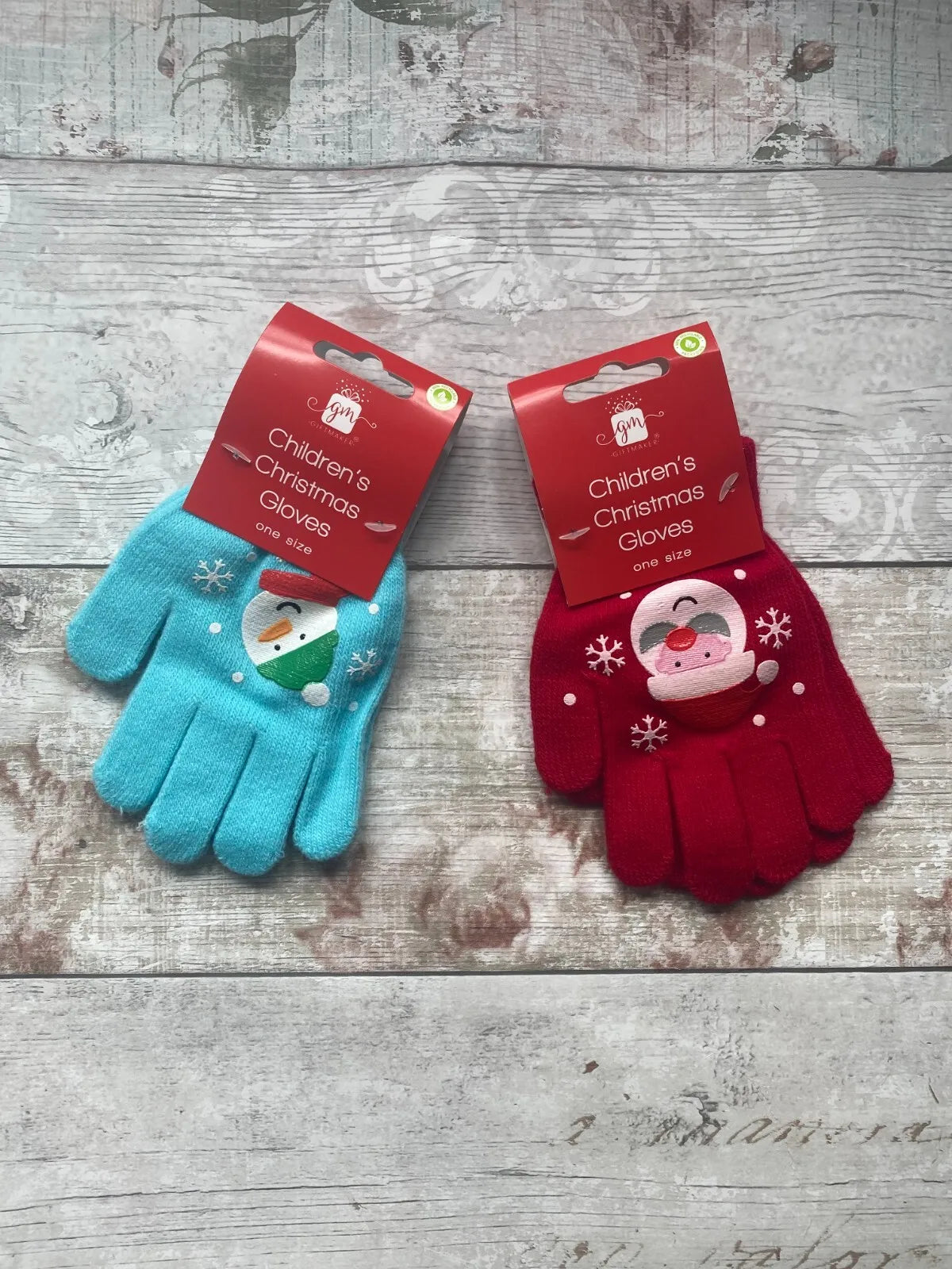 Two pairs of children's Christmas gloves, one in blue with a snowman design and the other in red with a Santa Claus design, both with festive snowflake patterns