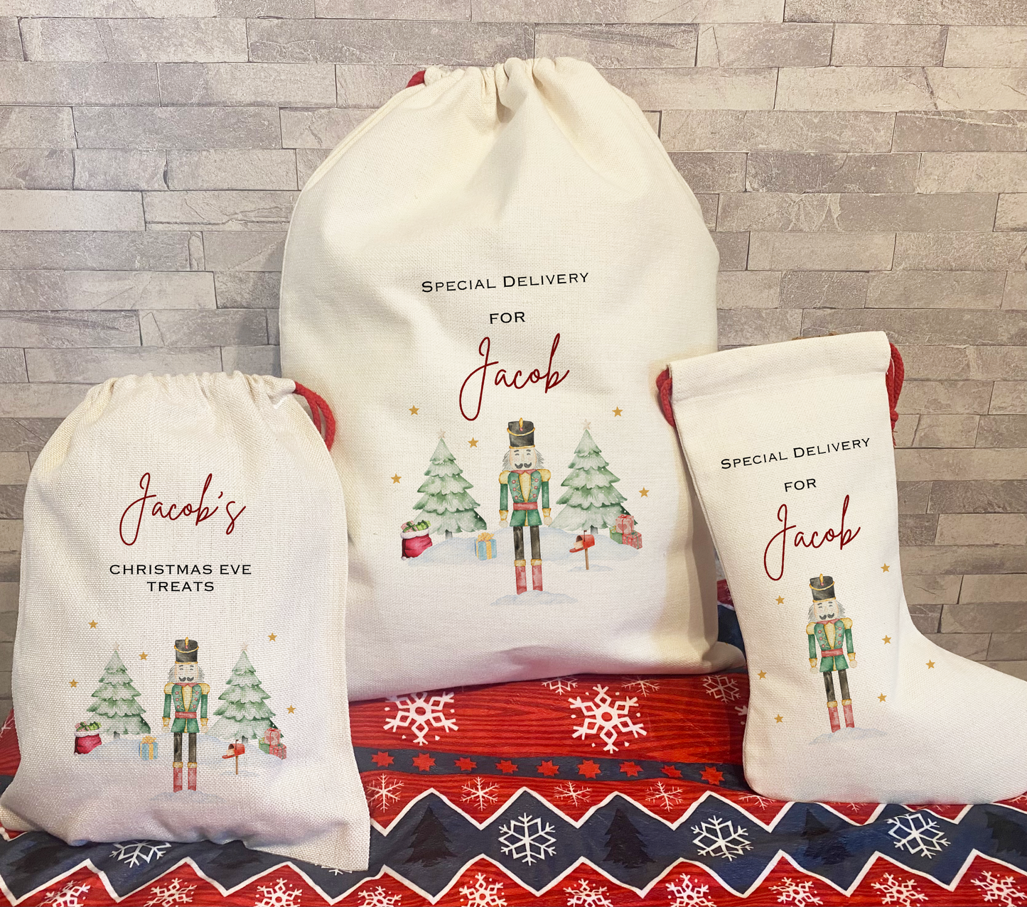 Set of three personalised Christmas gift bags, including a sack, stocking, and treat bag, each featuring the name “Jacob” and a festive nutcracker design with snowy trees, gifts, and gold stars – a magical custom holiday set for Christmas Eve.