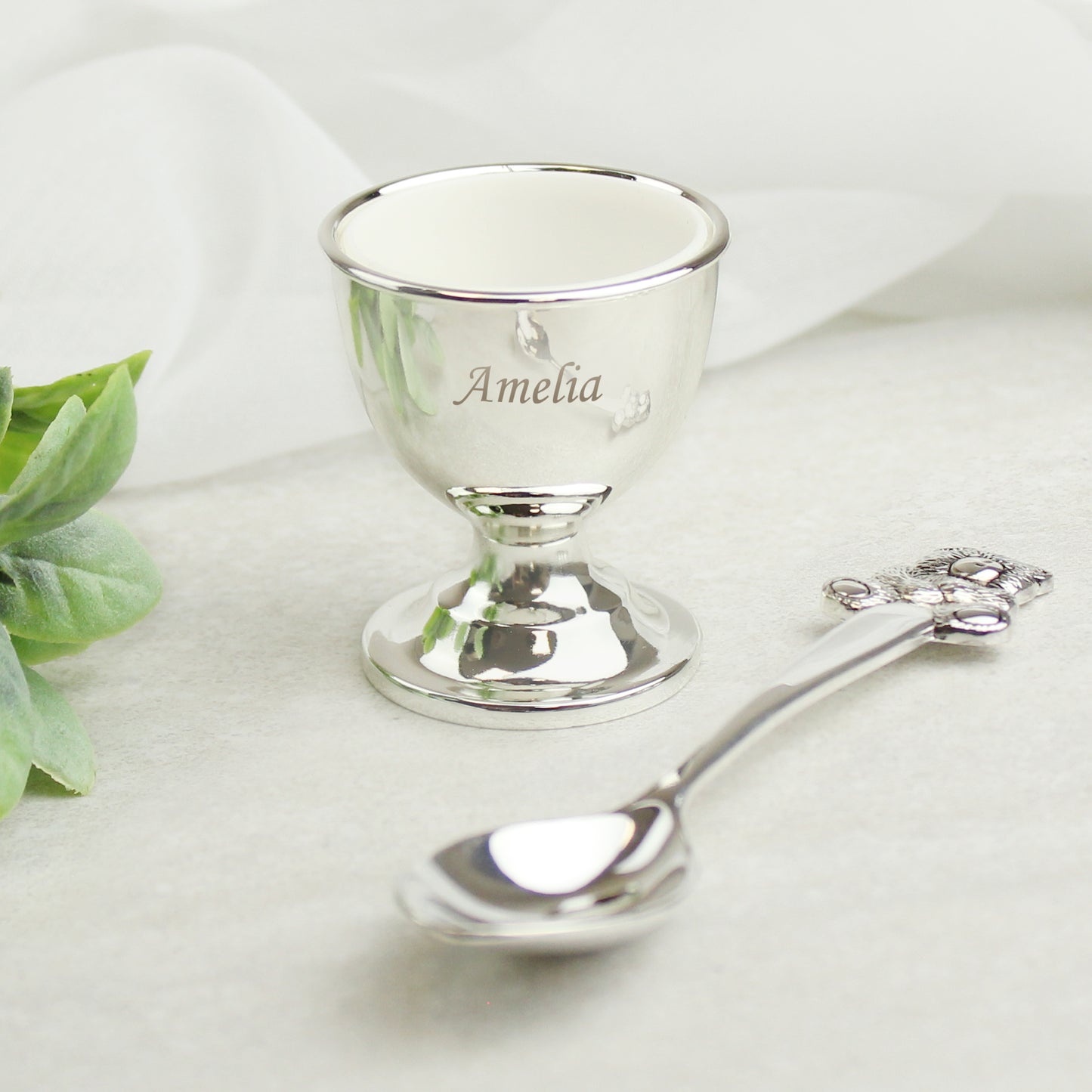 Silver egg cup and spoon with 'Amelia' on a white background