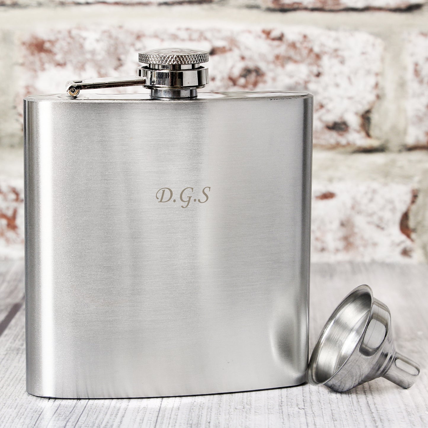 Stainless steel flask with funnel on a wooden surface