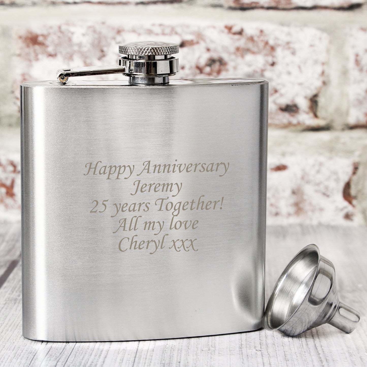 Stainless steel flask with engraved message on a wooden surface