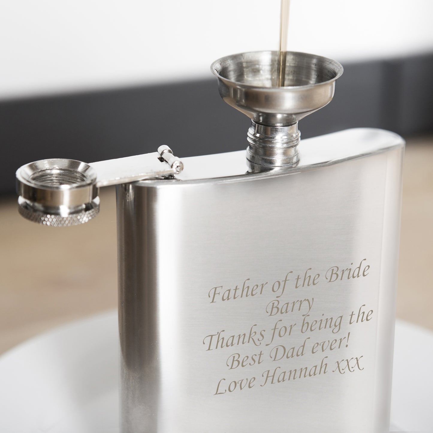 Stainless steel hip flask with engraved message on a white surface