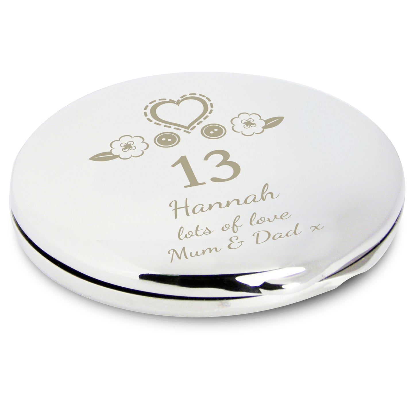 Silver compact mirror with engraved text and decorative elements on a white background