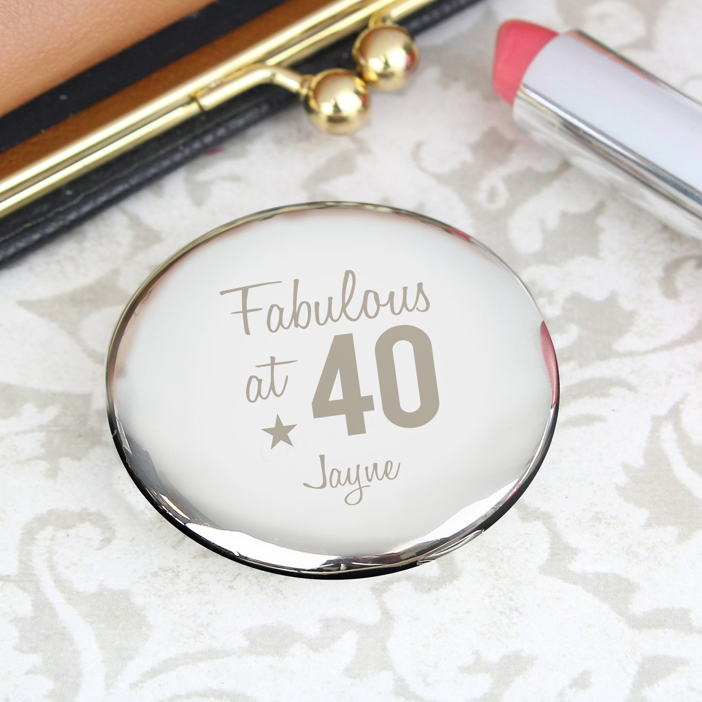 Compact mirror with 'Fabulous at 40' text on a textured white surface