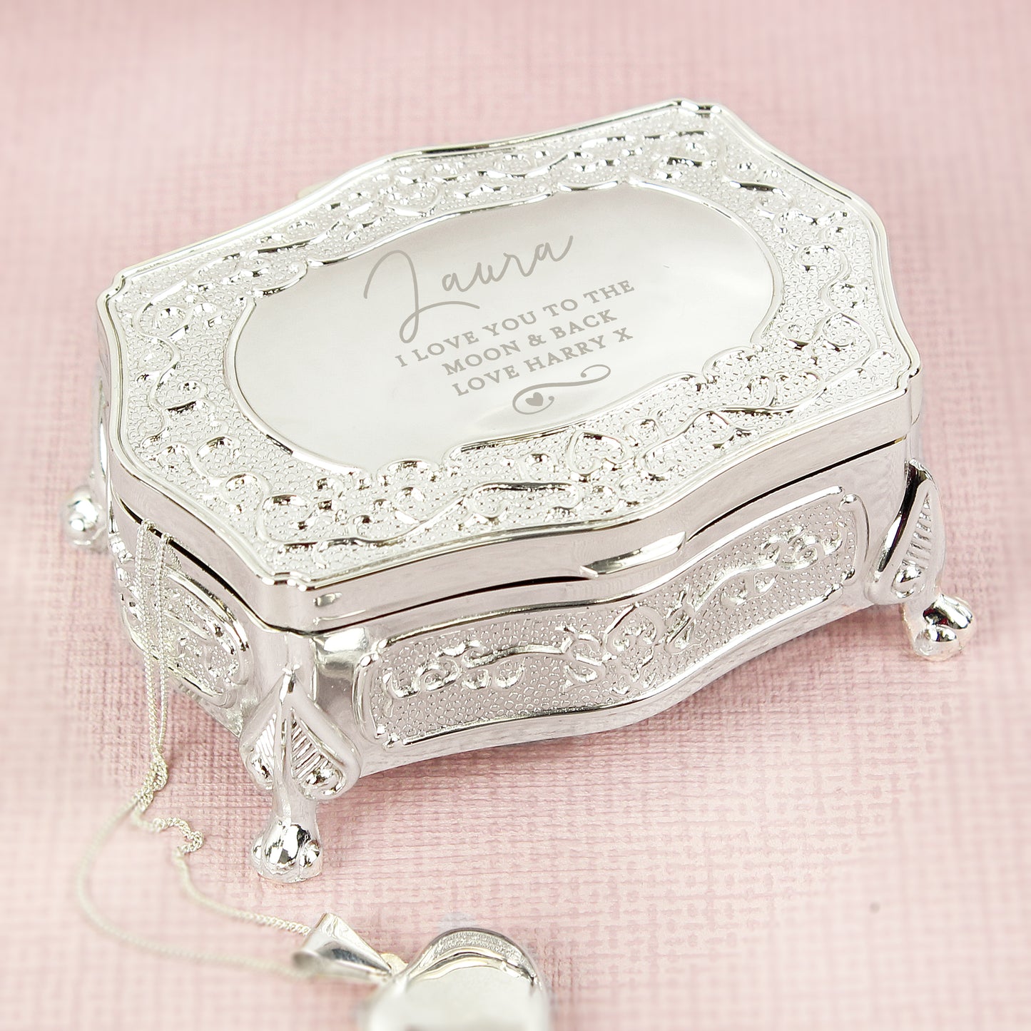 Silver jewellery box with engraved message on a pink background