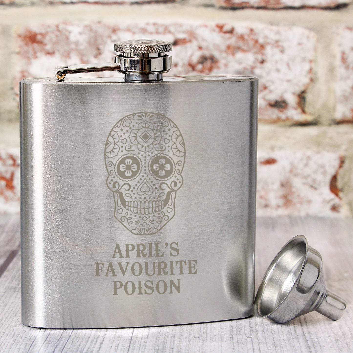 Stainless steel flask with skull design and 'April's Favourite Poison' text, accompanied by a funnel.
