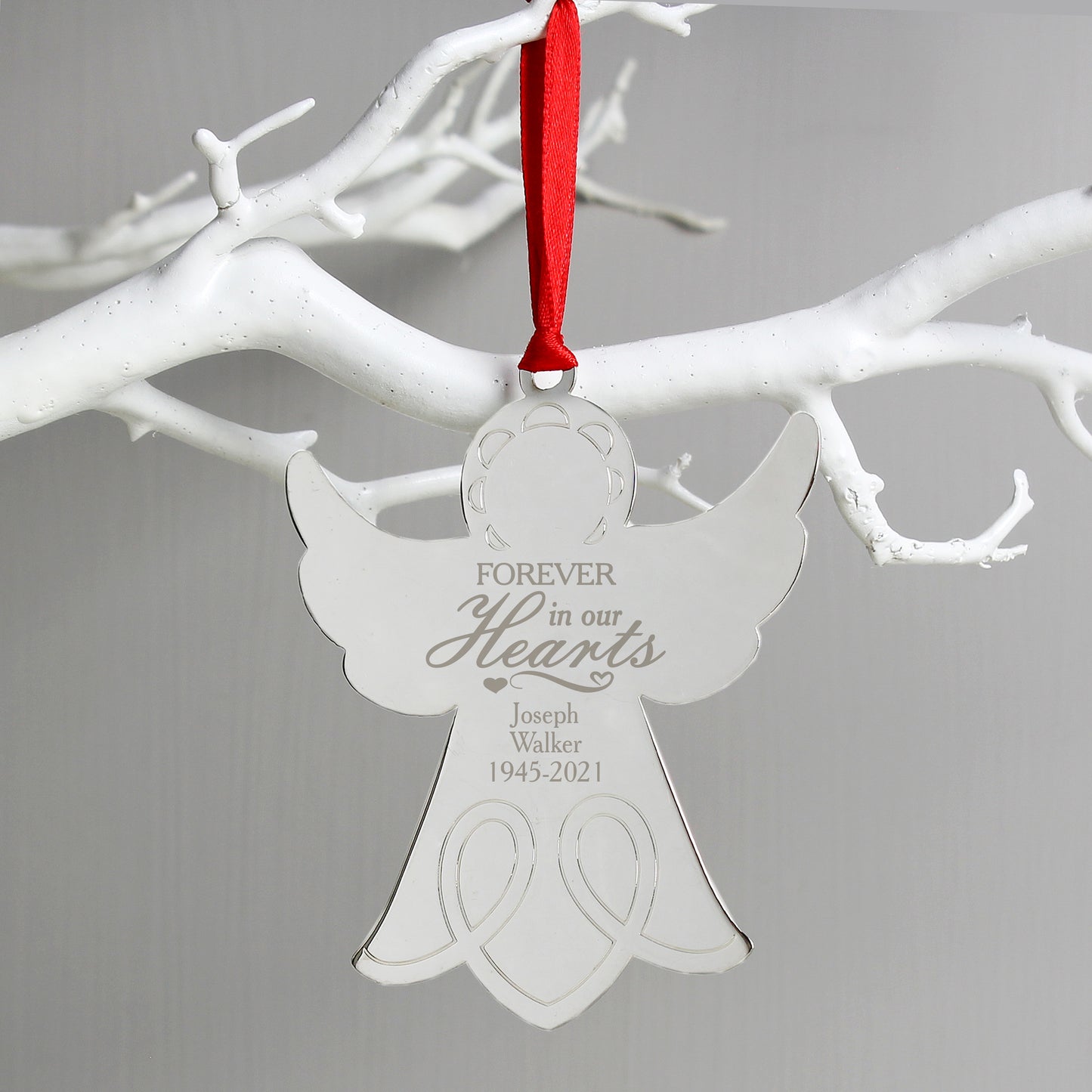Angel-shaped ornament with 'Forever in our Hearts' text on a white branch background