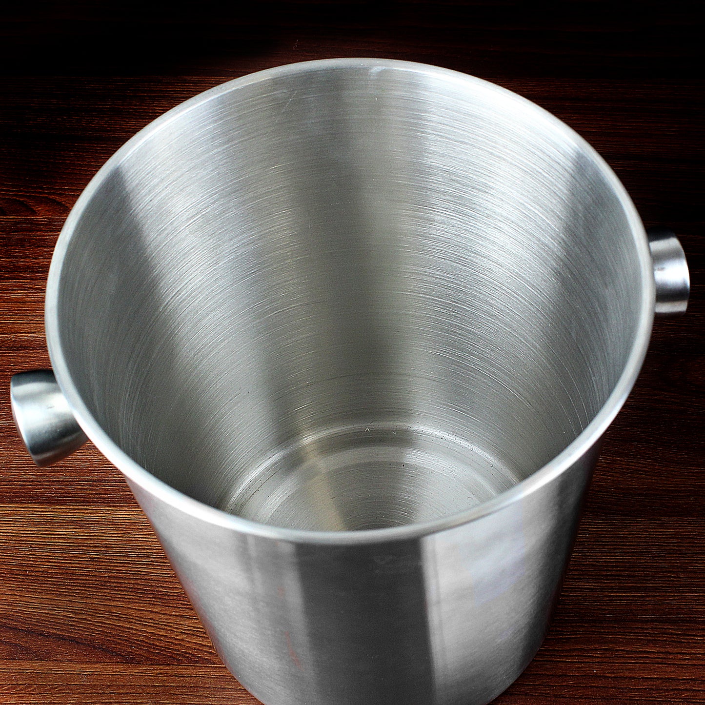 Stainless steel ice bucket on a wooden surface
