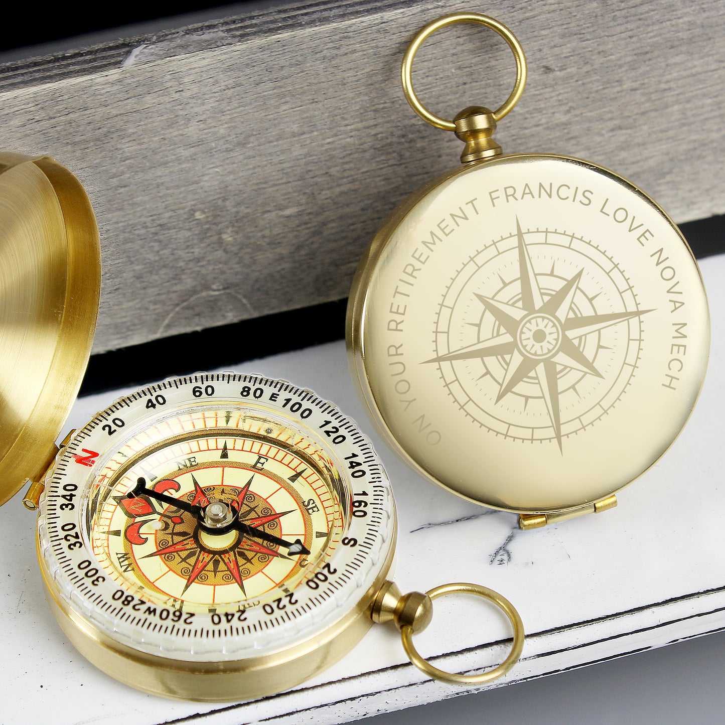 Two gold compasses on a wooden surface