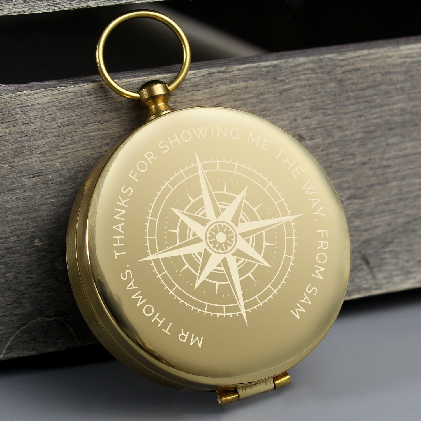 Personalised Gold compass with engraved text on a wooden surface
