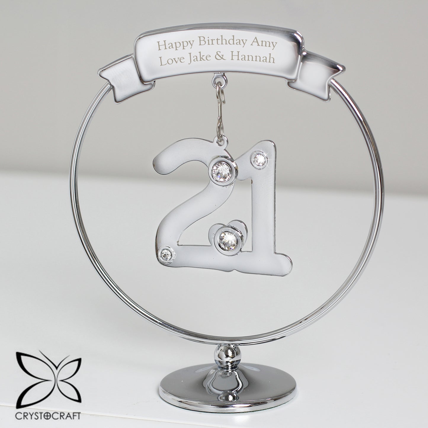 Silver '21' ornament with engraved text on a clear stand, featuring Crystocraft logo.