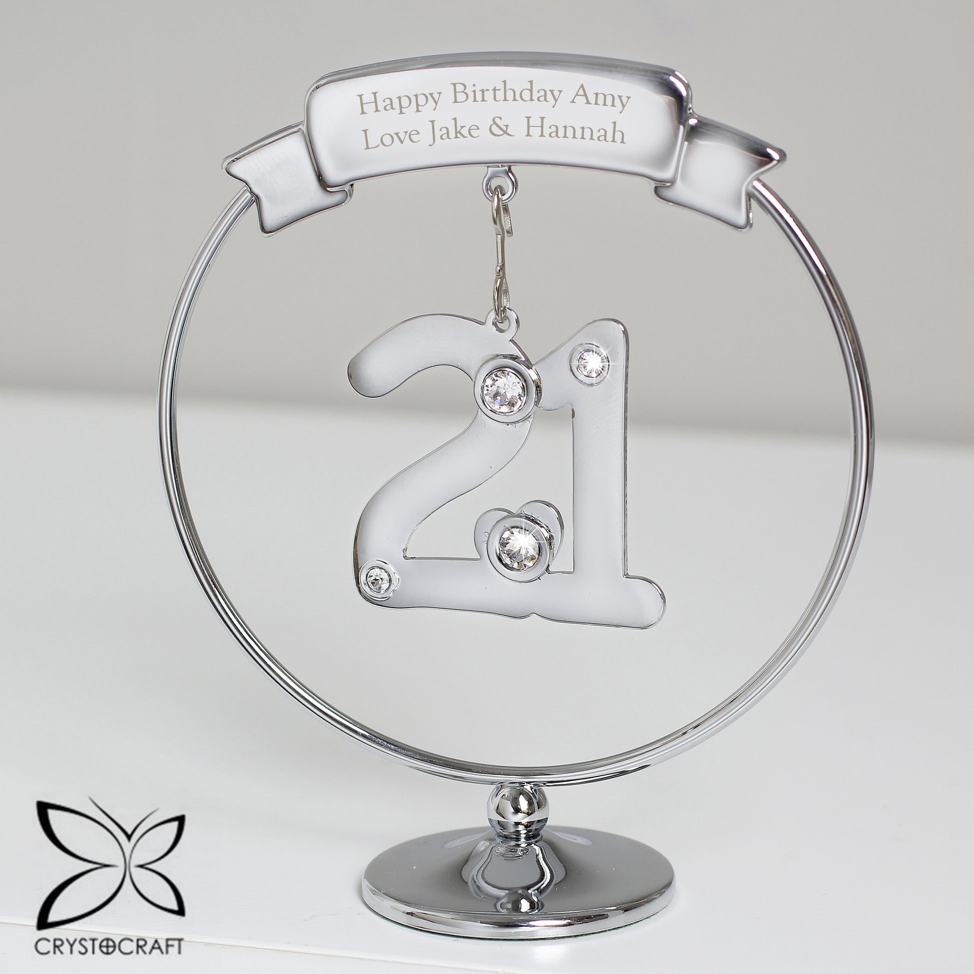 Silver '21' ornament with engraved text on a clear stand, featuring Crystocraft logo.
