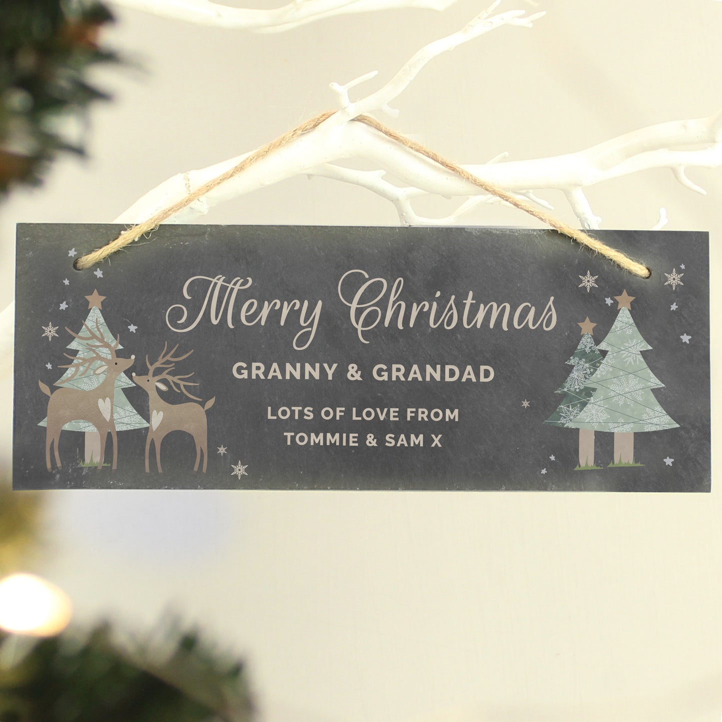 Personalised Christmas sign with reindeer and trees on a blurred Christmas tree background