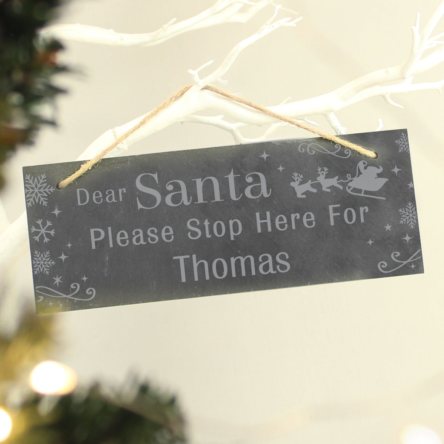Decorative sign for Christmas with 'Dear Santa Please Stop Here For Thomas' text, hanging on a branch.