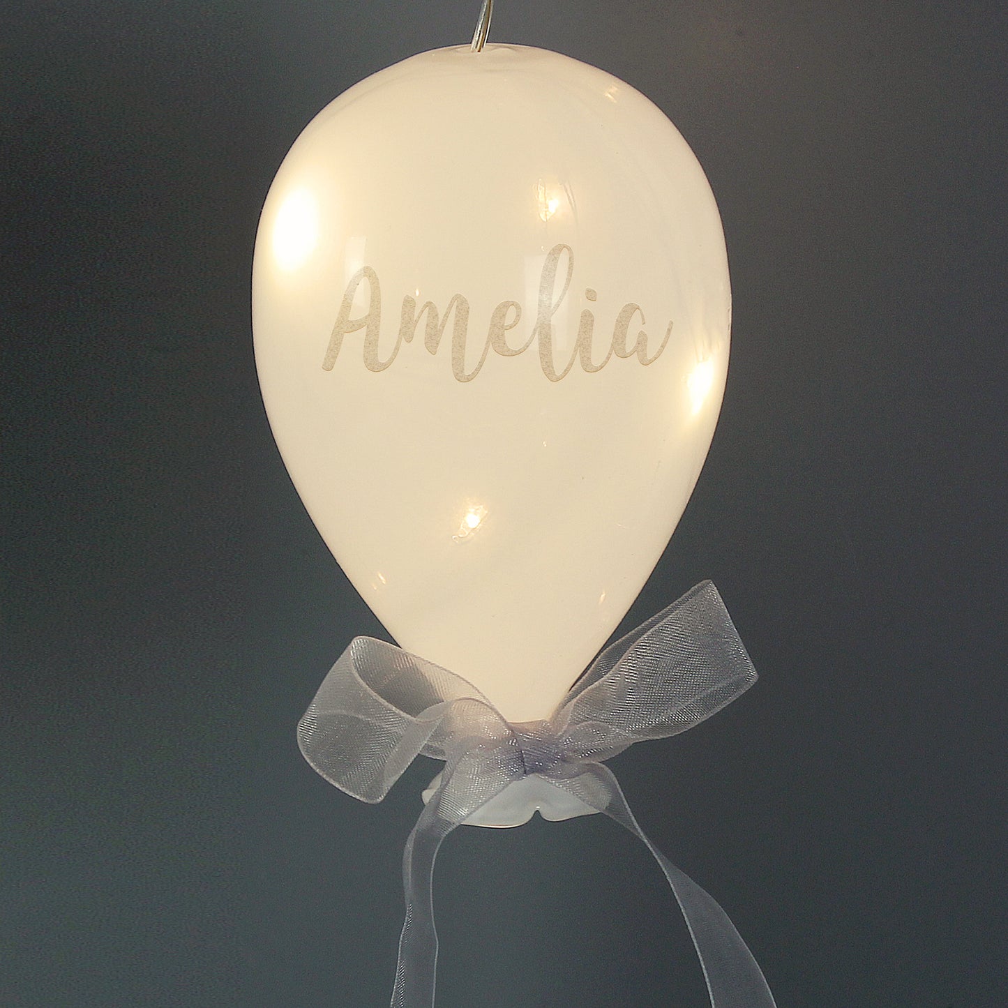 Decorative balloon with 'Amelia' written on it, featuring a bow against a dark background