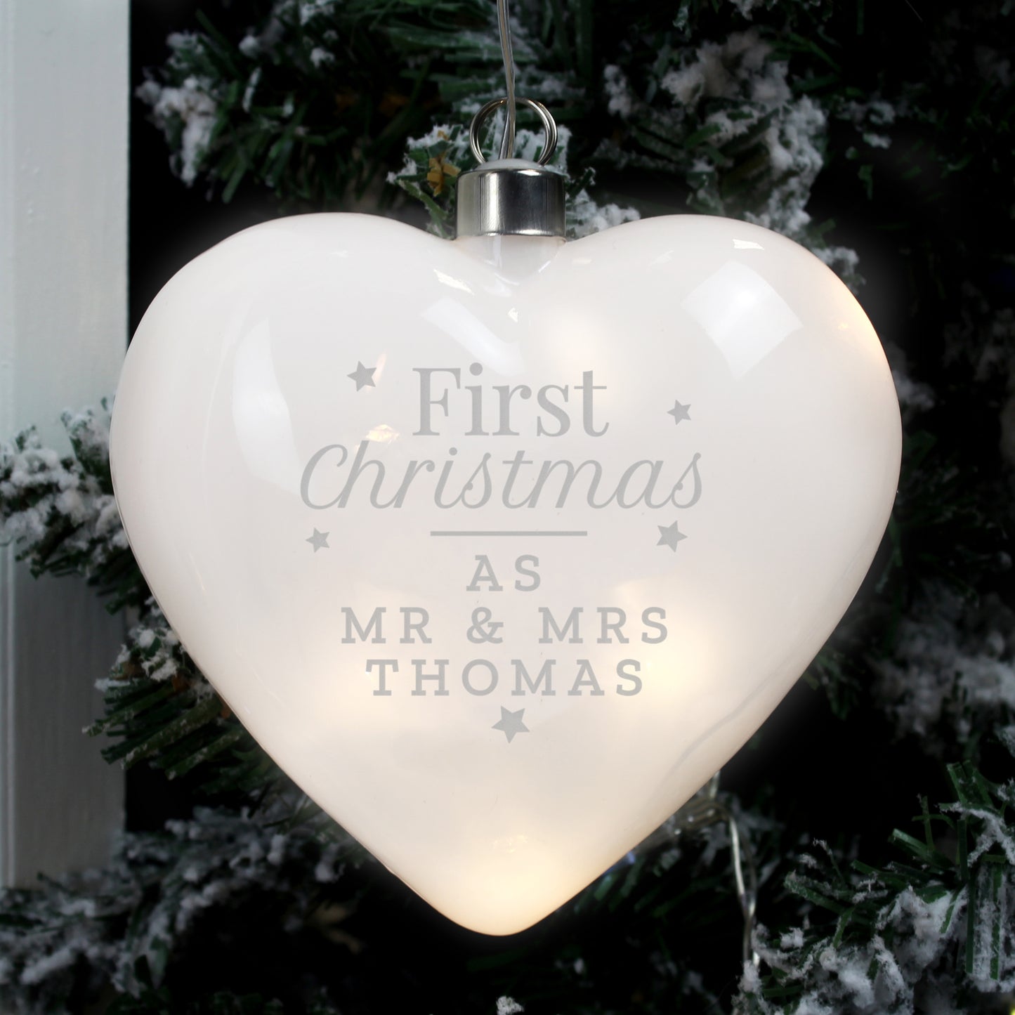 Heart-shaped LED ornament with 'First Christmas as Mr & Mrs Thomas' text, hanging on a tree.