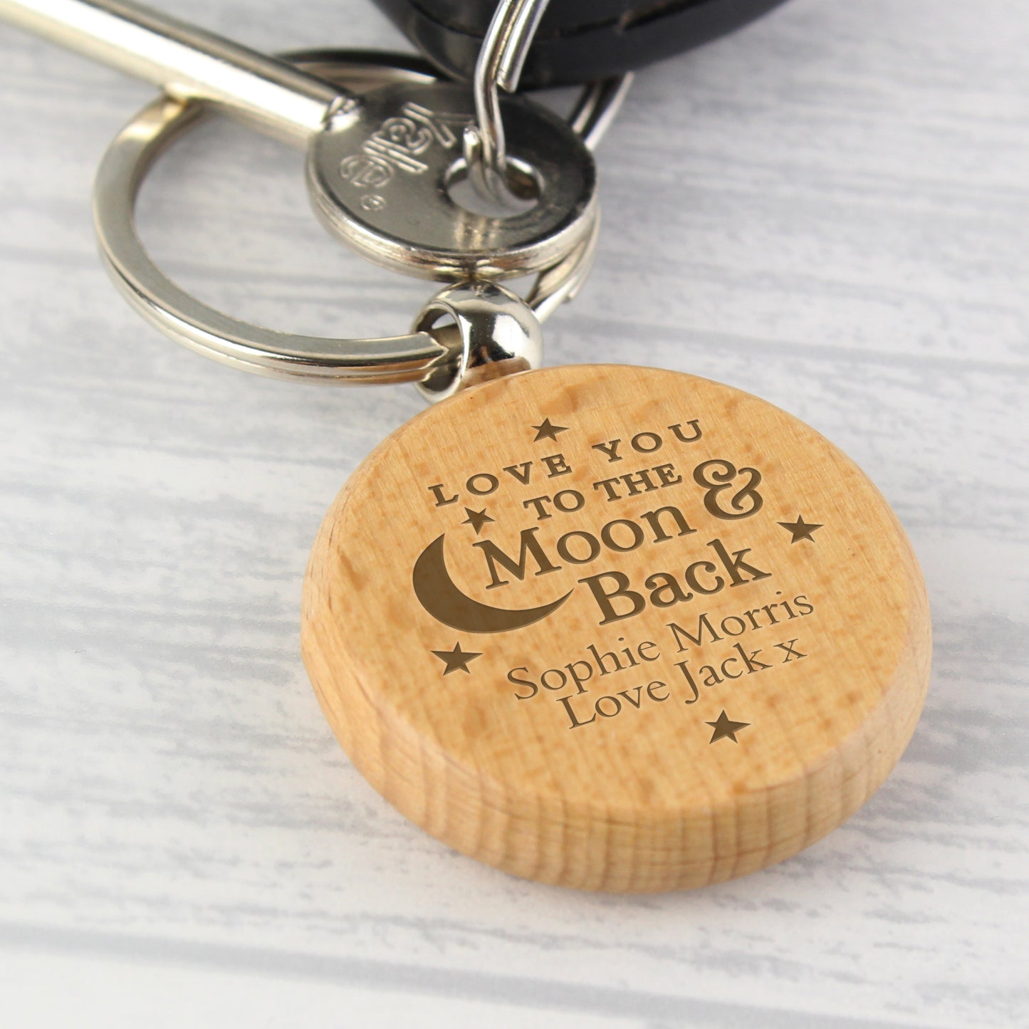 Wooden keychain with engraved message on a light gray background