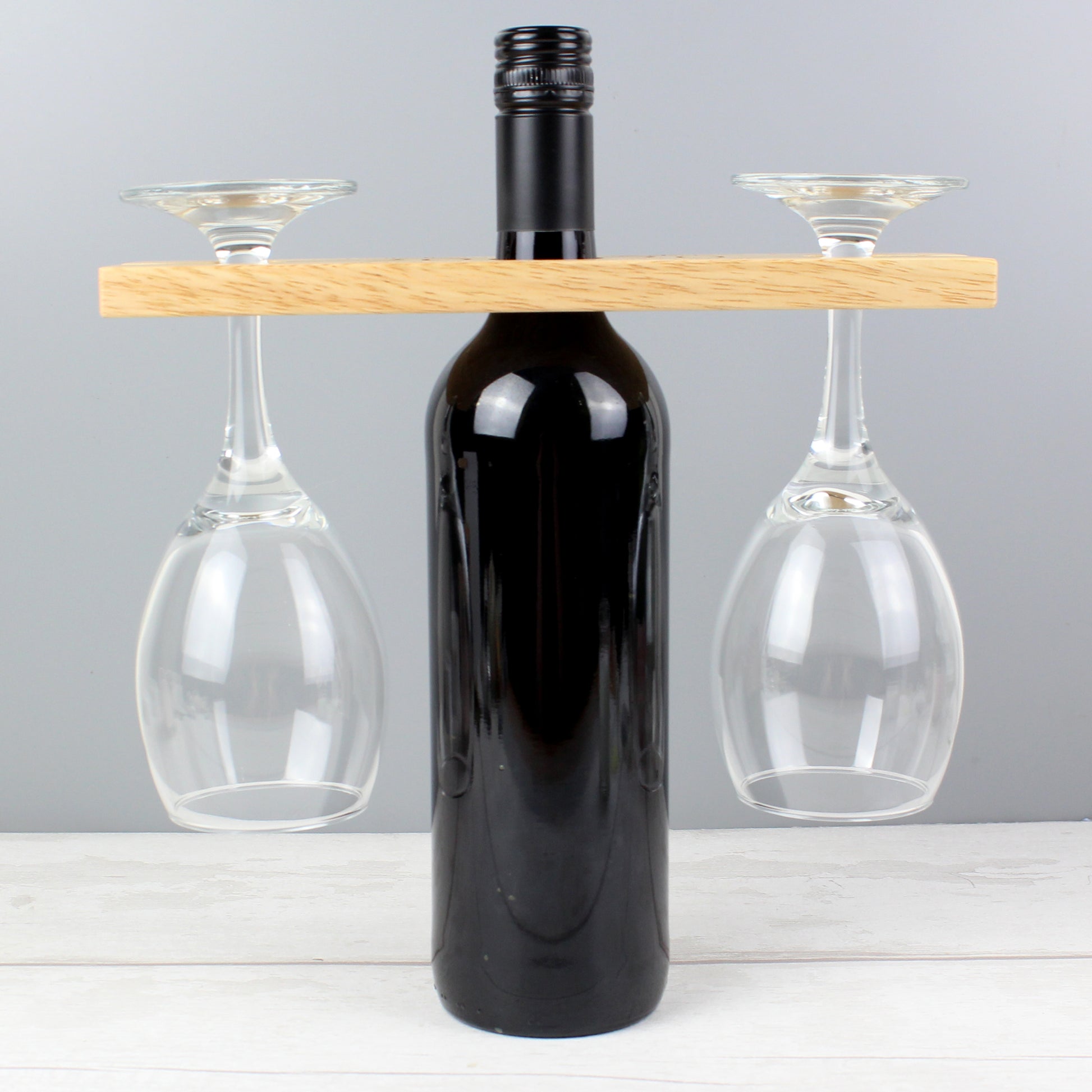 Wine bottle with two glasses on a wooden stand against a grey background