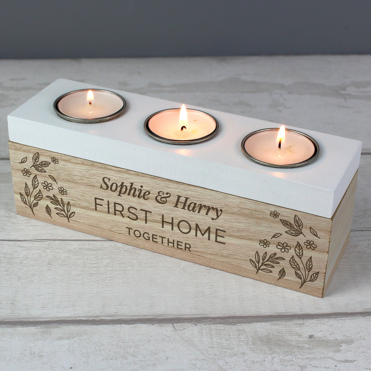 Three-wick candle holder with engraved text on a wooden base, featuring three lit candles.