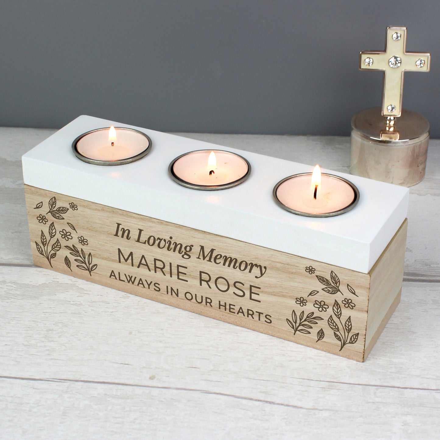 Candle holder with engraved text 'In Loving Memory MARIE ROSE ALWAYS IN OUR HEARTS' on a white surface.