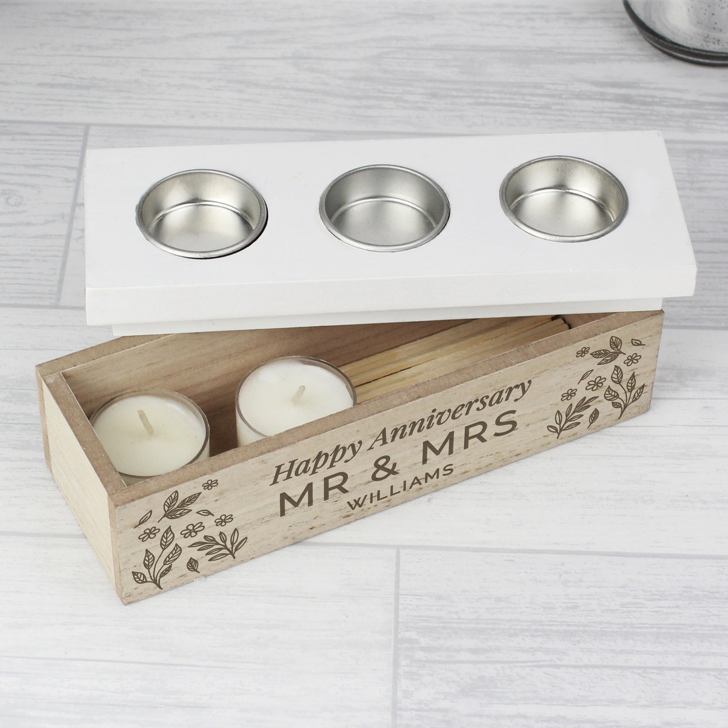 Personalised candle holder set with three candles and a wooden box engraved with 'Happy Anniversary MR & MRS WILLIAMS' on a light gray surface.