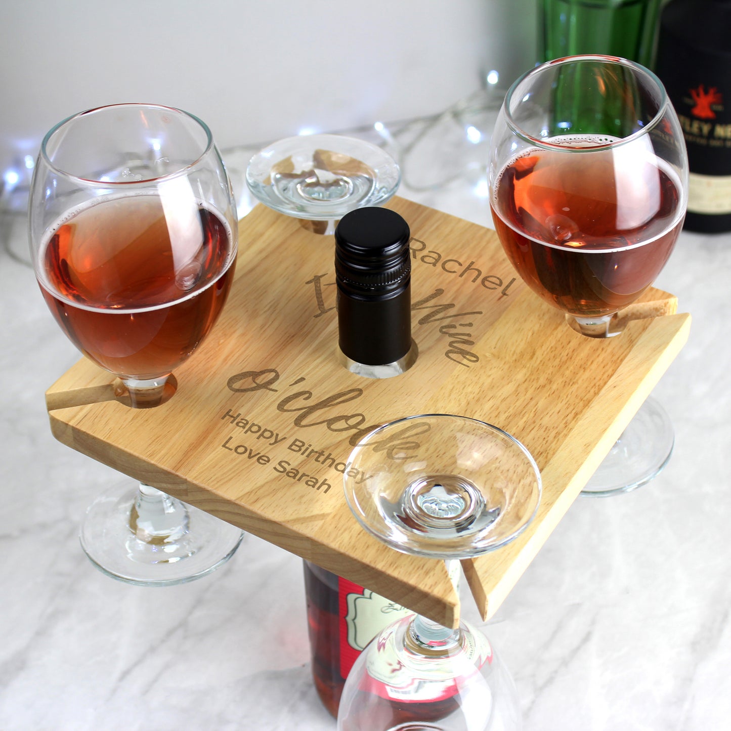 Wooden tray with glasses of red wine and a bottle on a white surface
