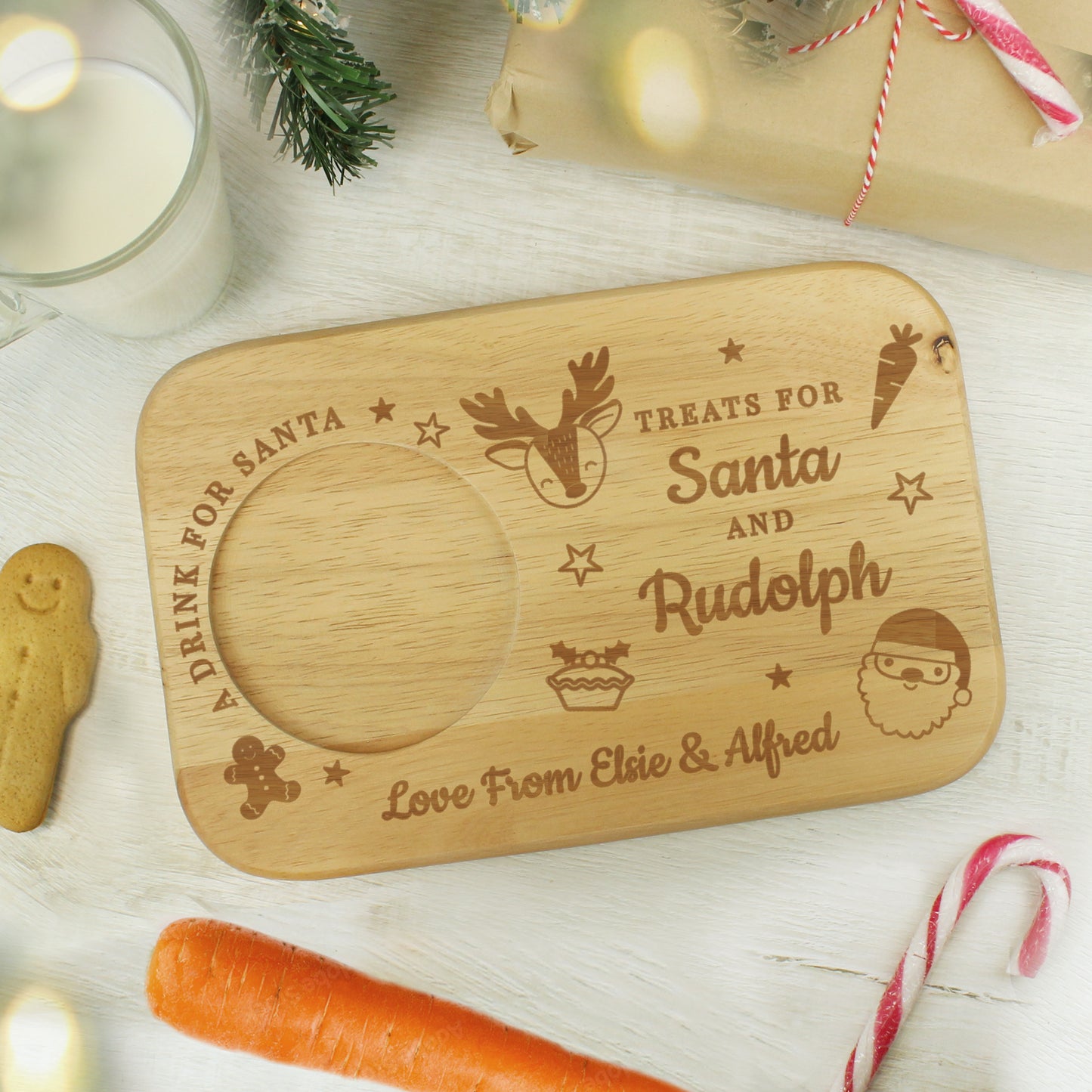 Wooden tray with engraved text and Christmas-themed illustrations on a festive background.