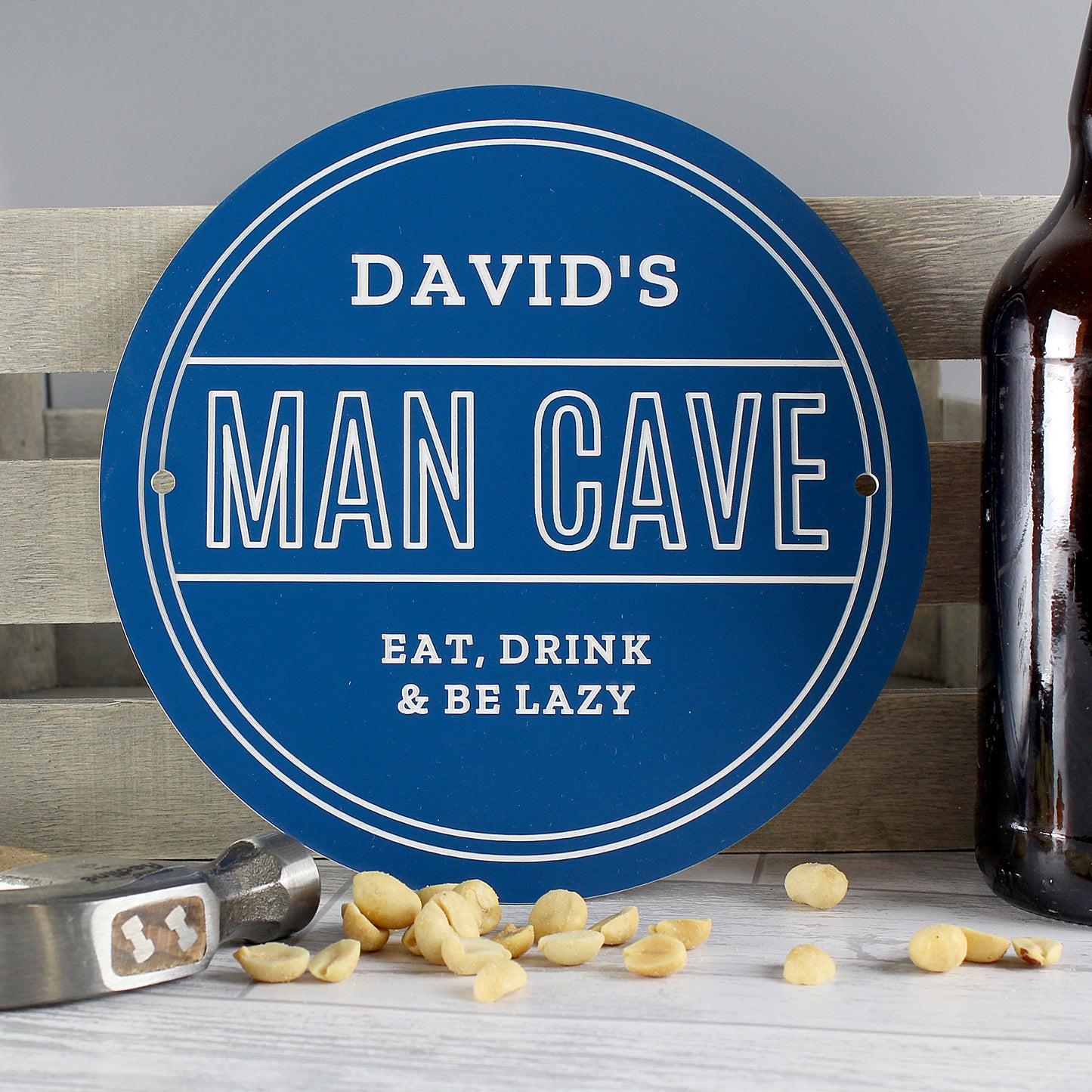 Circular sign with 'DAVID'S MAN CAVE EAT, DRINK & BE LAZY' text on a wooden bench.