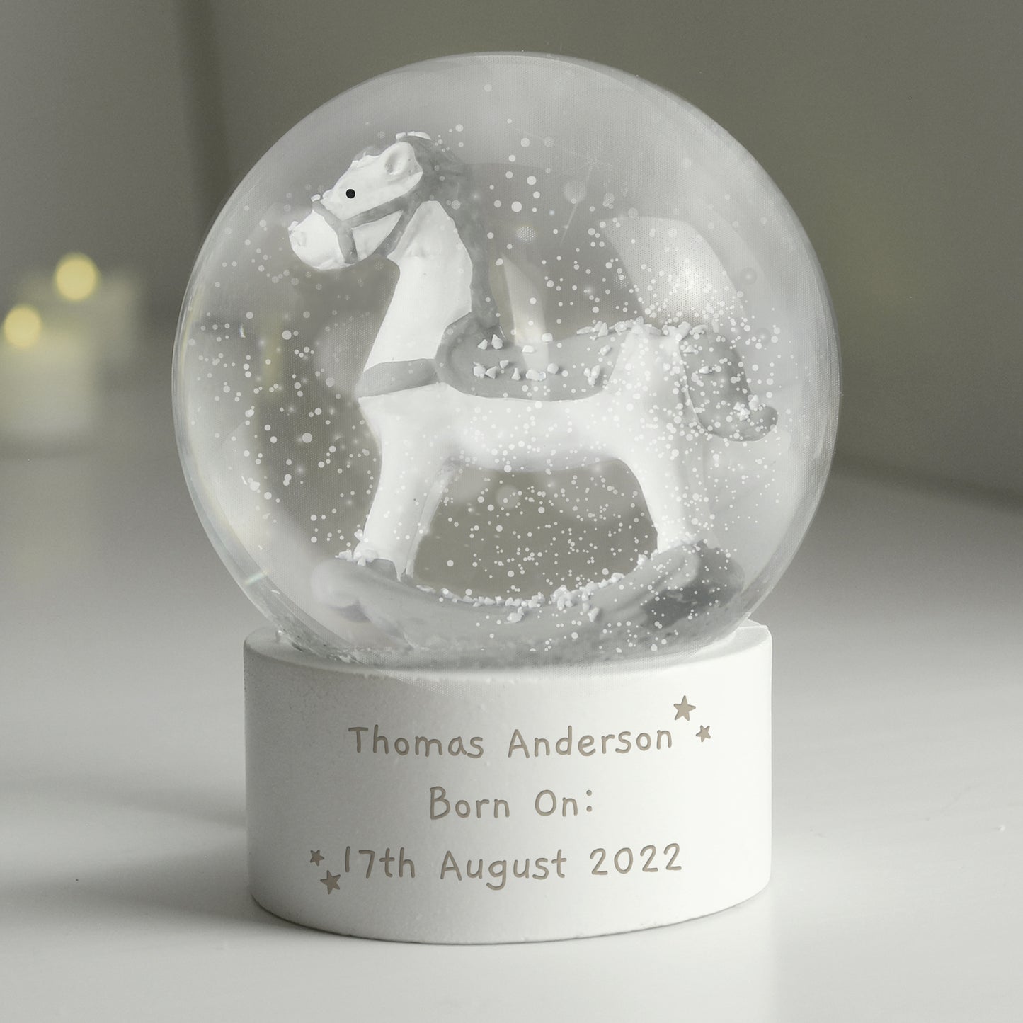 Snow globe with a horse figure and engraved text on a white surface