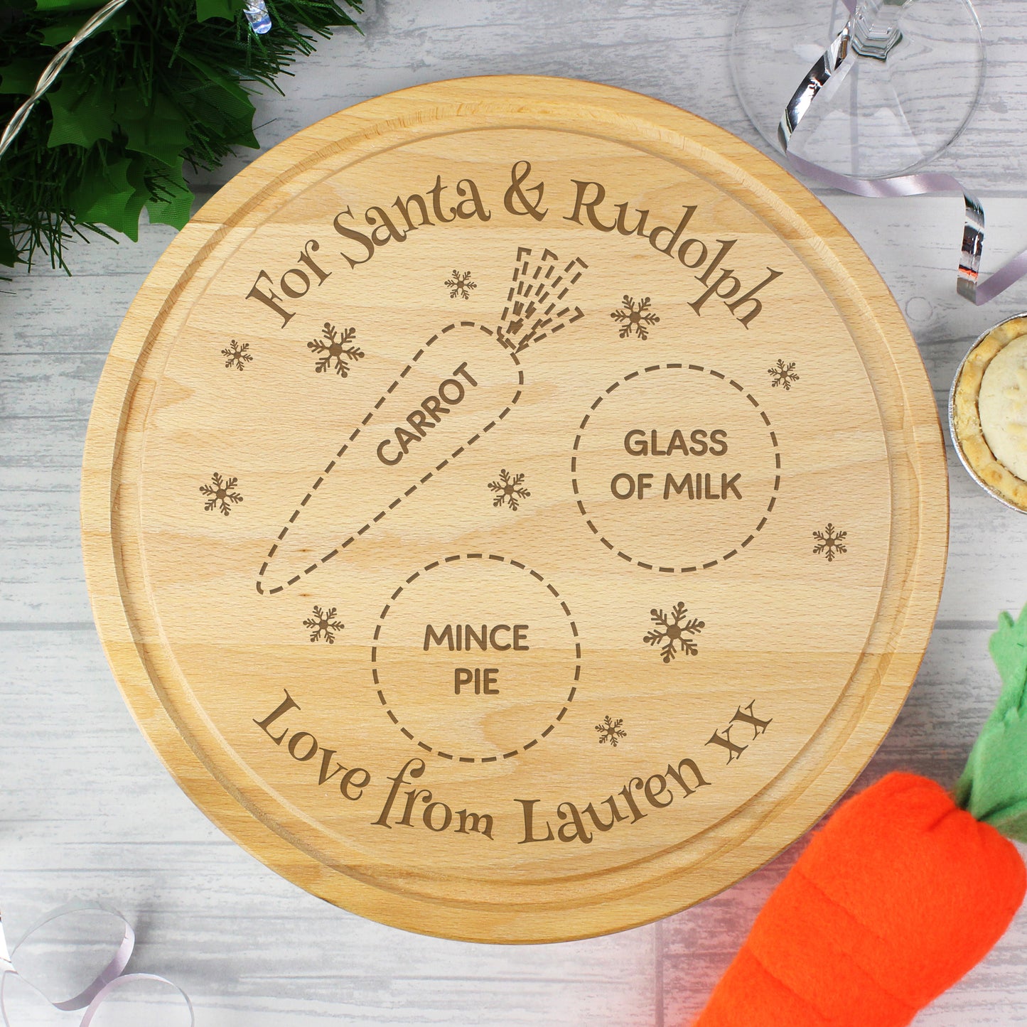 Wooden round tray with engraved text for Santa and Rudolph, placed on a table with a carrot and glass of milk.