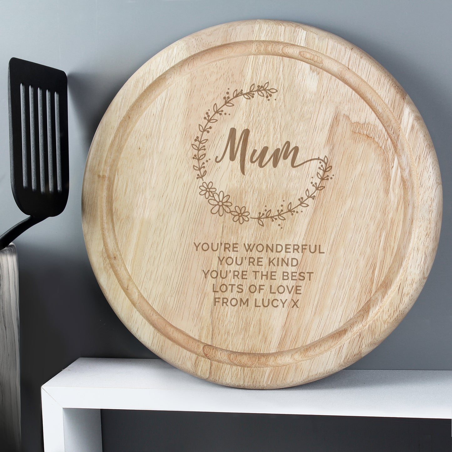 Wooden cutting board with engraved message on a kitchen shelf