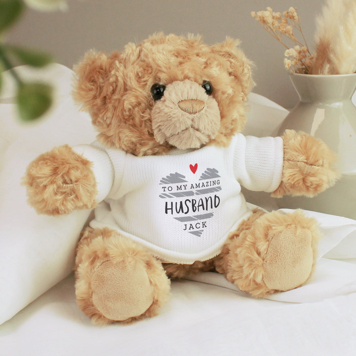 Teddy bear wearing a shirt with personalised message on a light background