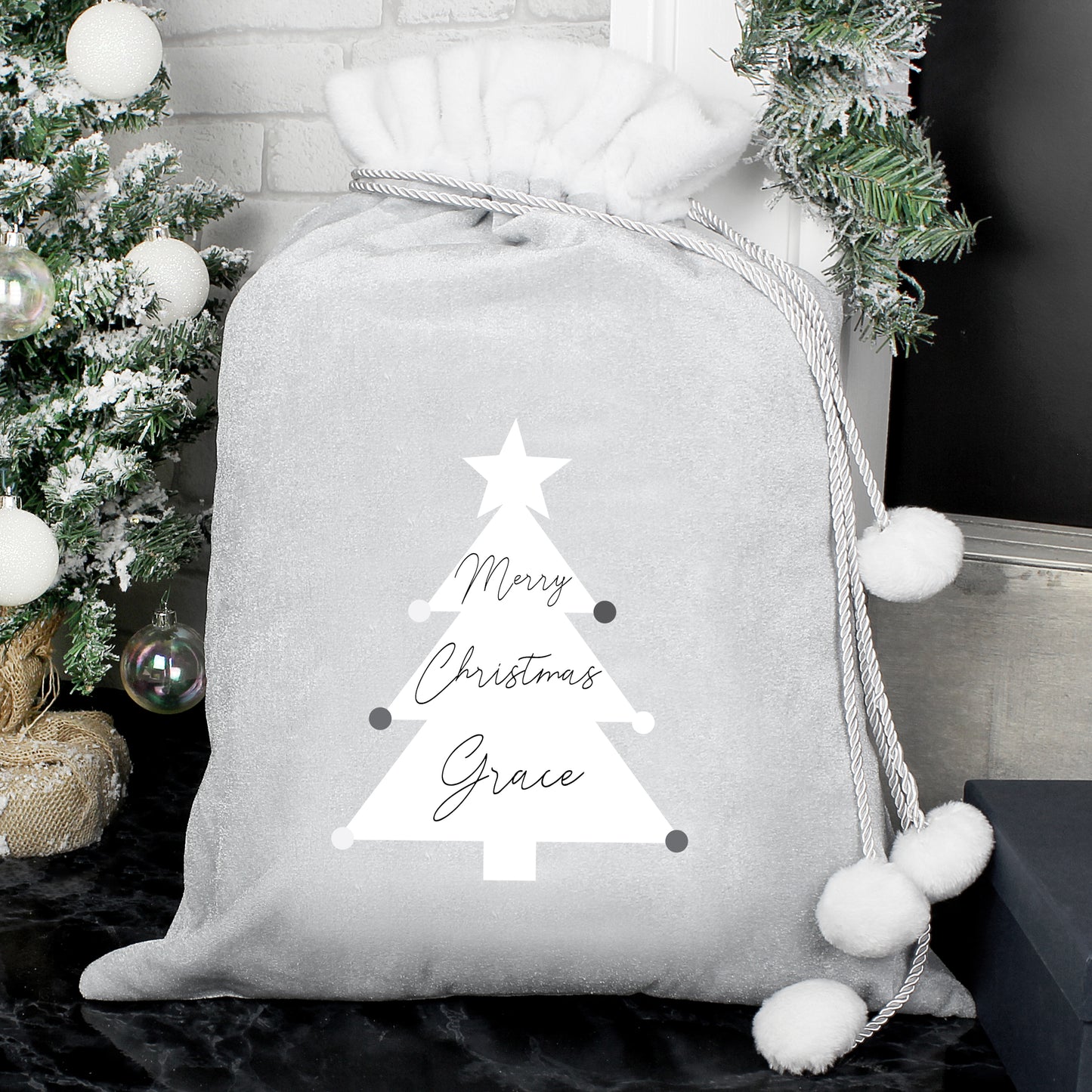Gray gift sack with a Christmas tree design and 'Merry Christmas Grace' text, placed against a festive background.