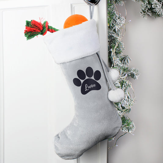 Gray Christmas stocking with a paw print and 'Luna' text, hanging on a white door with festive decorations.