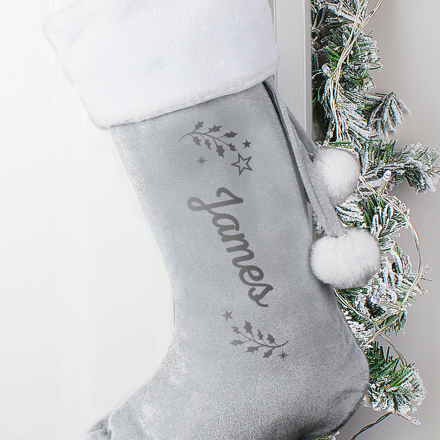 Grey Christmas stocking with 'James' embroidered on it, hanging against a neutral background.