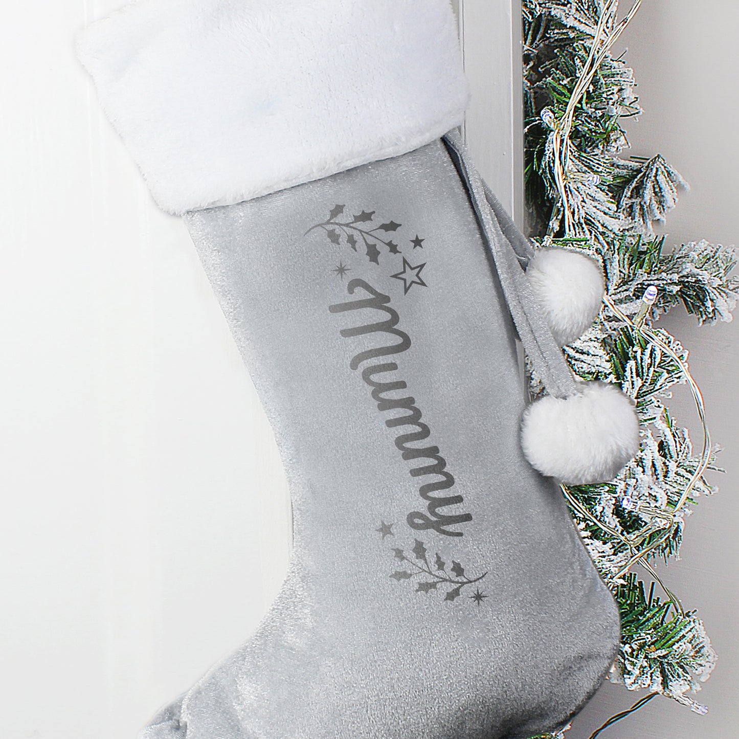Personalised Grey Christmas stocking with 'mummy' and pom-poms, against a neutral background.